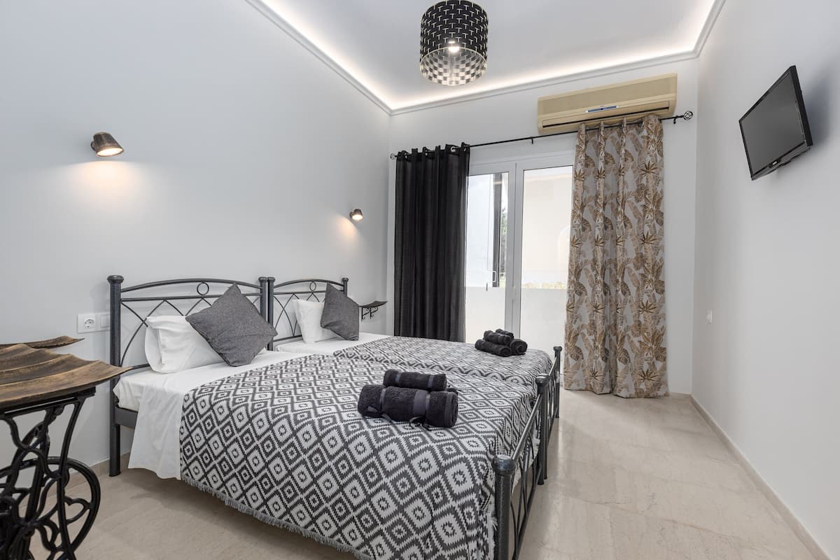 A modern bedroom with a bed, bedside tables, a desk, and a TV.