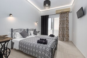 A modern bedroom with a bed, bedside tables, a desk, and a TV. - Anya Studios by Estia (Corfu)