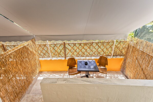 A covered outdoor seating area with a table and chairs, surrounded by a patterned fence. - Anya Studios by Estia (Corfu)