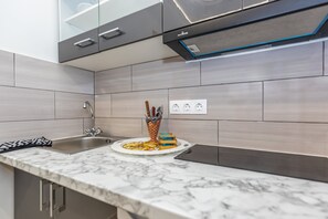 A modern kitchen with a marble countertop, stainless steel sink, and a built-in oven. - Anya Studios by Estia (Corfu)