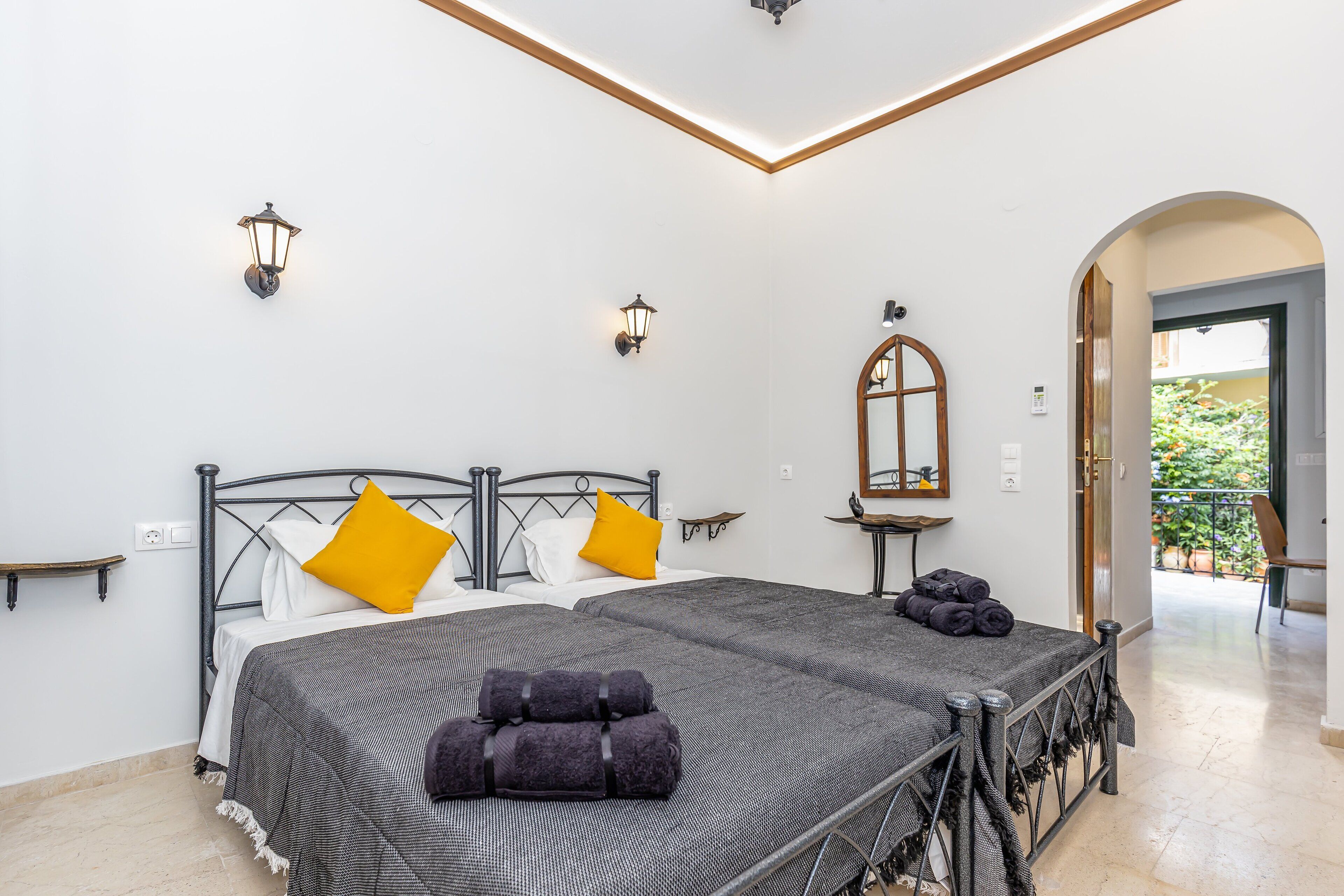 Une chambre à coucher avec un lit, deux lampes fixées au mur, un miroir et une vue sur l’extérieur.
