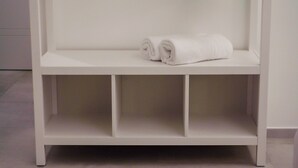 A white shelf with two rolled towels on it.