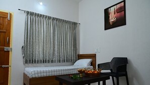 Une petite chambre à coucher, bien rangée, avec un lit simple, une table sur laquelle se trouve un panier de pain et une chaise.