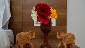Une table de chevet en bois, ornée d’un vase de fleurs et de deux statuettes d’éléphants.