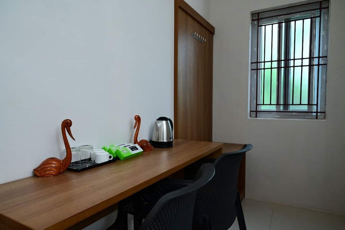 A wooden table with a kettle, cups, and a green box, flanked by two swan-shaped objects.