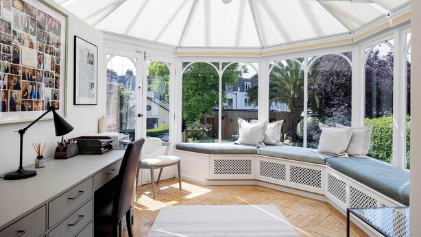 A conservatory with a curved bench, a desk, and a chair. - Majestic in Kensington, by Veeve (London)