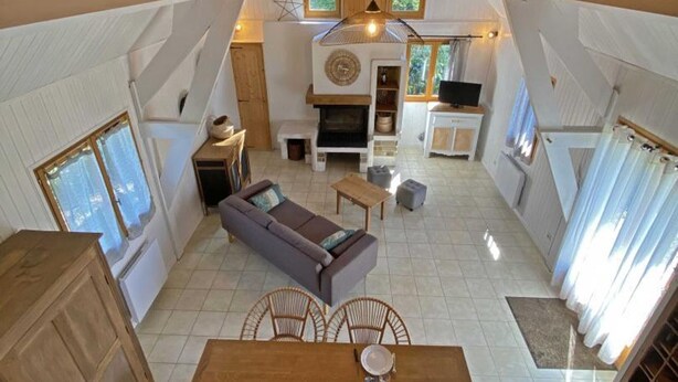 A spacious living area with a sofa, dining table, and chairs, a fireplace, and a television. - Cozy wooden chalet in the forest, perfect for couples (Chaumont)