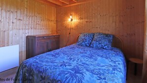 A wooden room with a bed, a nightstand, and a wall-mounted light fixture. - Cozy wooden chalet in the forest, perfect for couples (Chaumont)