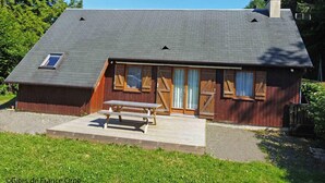 A single-story wooden house with a sloped roof, a front porch, and a small attached shed. - Cozy wooden chalet in the forest, perfect for couples (Chaumont)