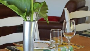 A dining table with a vase of white flowers, two wine glasses, and a plate with a floral pattern. - Charming house in Monnai, pets allowed, garden and terrace (La Ferté-en-Ouche)