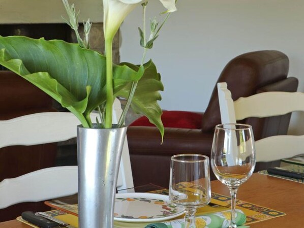 A dining table with a vase of white flowers, two wine glasses, and a plate with a floral pattern.