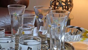 A table with several clear glasses, some with embossed designs, and a decorative lamp in the background. - Charming house in Monnai, pets allowed, garden and terrace (La Ferté-en-Ouche)