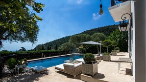 Un espace piscine privé avec des chaises longues, une table et des plantes en pot.