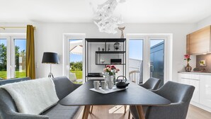Un espace repas moderne avec une table noire, des chaises grises et un plaid en fausse fourrure blanche.