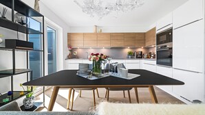 Une cuisine moderne avec des meubles en bois, une table à manger noire et un lustre.