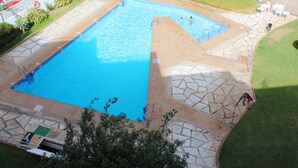 A swimming pool with a tiled deck, surrounded by a grassy area and a few buildings. - M & M Neptuno Torrecilla Beach. With Pool (Nerja)