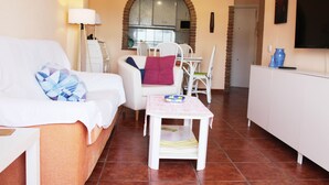 A cozy living area with a white sofa, a small table with a bowl, and a white cabinet. - M & M Neptuno Torrecilla Beach. With Pool (Nerja)