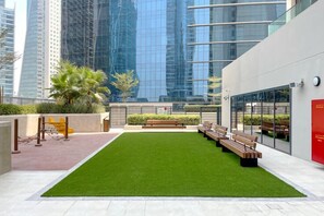 Un jardin sur le toit, avec du gazon synthétique, des bancs et des palmiers.