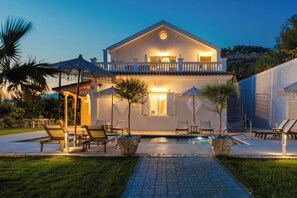 A two-story house with a swimming pool, outdoor seating, and a well-maintained garden. - Pantheon Villa (kefalonia)