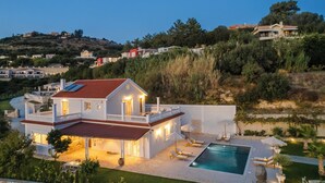 Una casa grande con piscina, un porche cubierto y vistas del paisaje circundante.