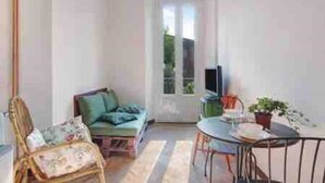 Un salon avec un canapé, un fauteuil, une petite table et un téléviseur.