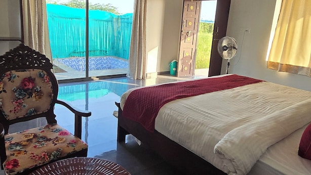 Une chambre d’hôtel avec un lit, une chaise, une table et une vue sur une piscine.