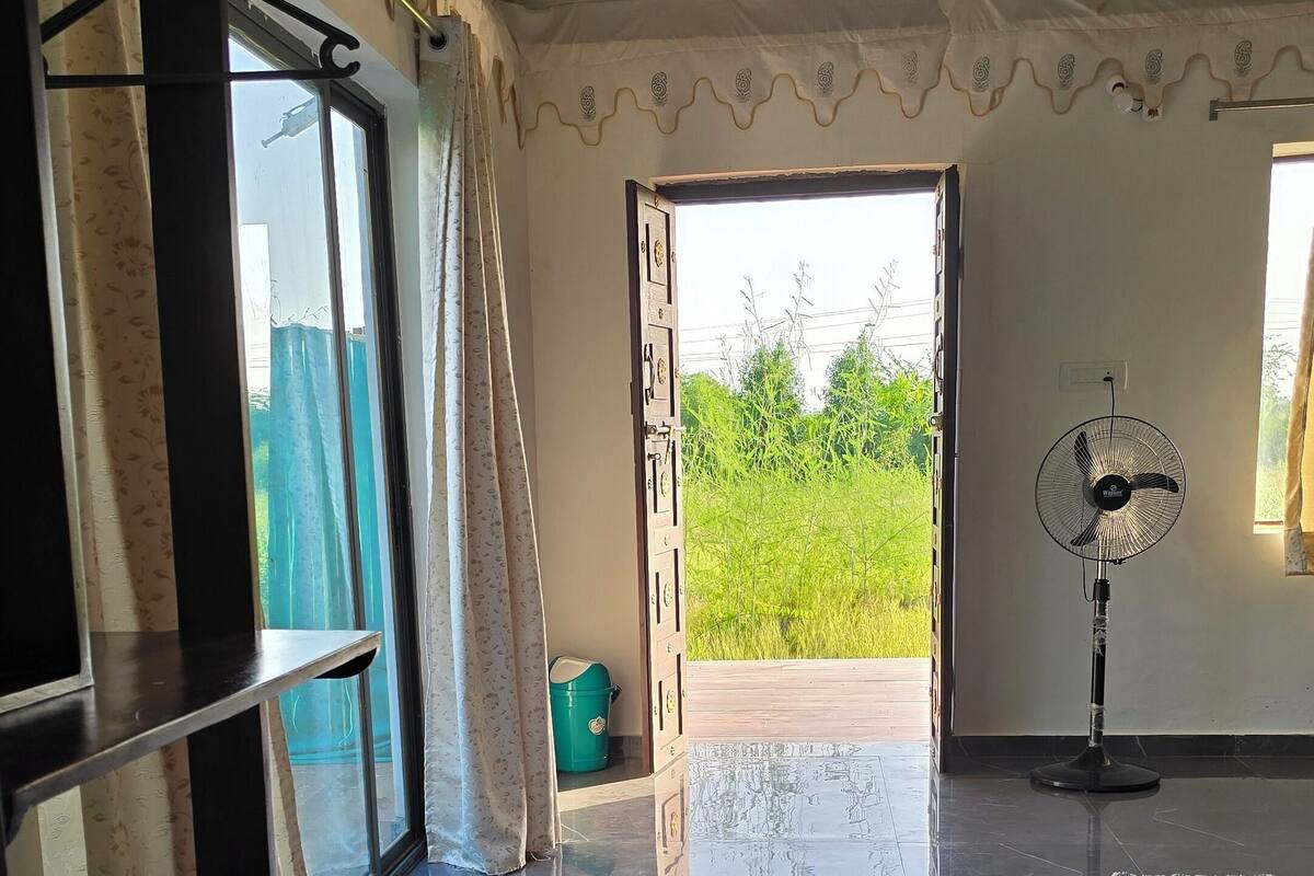 A room with a marble floor, a fan, and a view of greenery outside.