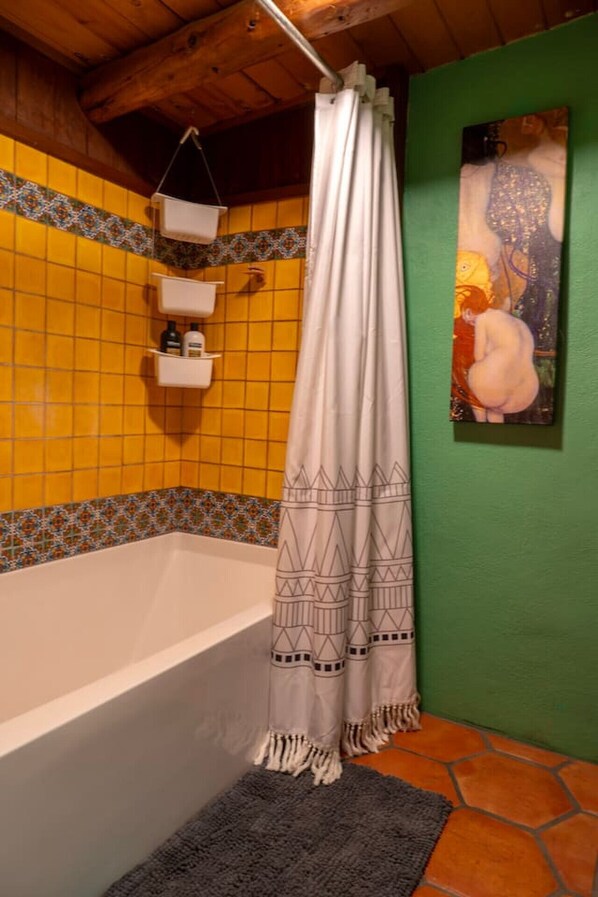 Un baño con bañera, cortina de ducha y pared de azulejos.