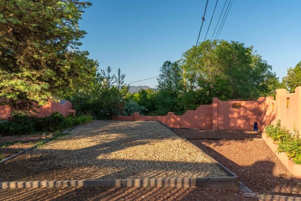 Un camino de grava que conduce a un edificio con pared exterior roja y terraza de madera.