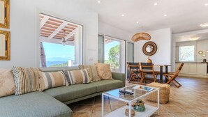 A modern living room with a green sofa, a glass coffee table, and a dining area with wooden chairs. - Petramar by Interhome (Lloret de Mar)