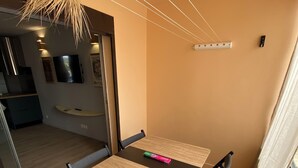 A dining area with a table and chairs, a television mounted on the wall, and a kitchen visible through an open door.