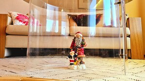 Une pièce dans laquelle une petite figurine du Père Noël et d’un enfant est placée sous une cloche de verre transparente.