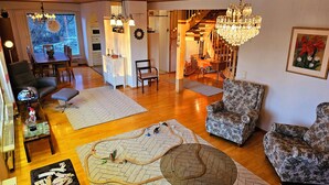 Un salon chaleureux avec un plancher en bois, un coin repas et un escalier menant à un autre niveau.