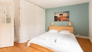 A bedroom with a bed, a painting on the wall, and a curtain. - “Keep the magic going after Disney” (Saint-Germain-sur-Morin)