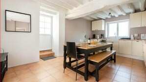 A dining area with a wooden table and chairs, a kitchen in the background, and a window providing natural light. - “Keep the magic going after Disney” (Saint-Germain-sur-Morin)