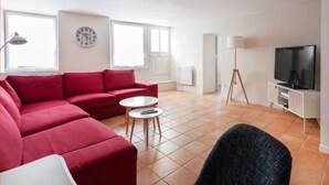 A living room with a red sofa, a small round table, a television, and a lamp. - “Keep the magic going after Disney” (Saint-Germain-sur-Morin)