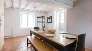 A dining area with a wooden table set for four, white walls, and a white ceiling. - “Keep the magic going after Disney” (Saint-Germain-sur-Morin)
