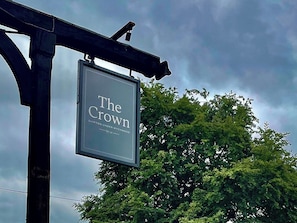 A sign for 'The Crown' pub with a view of trees in the background. - The Crown at Shipton (Chipping Norton)