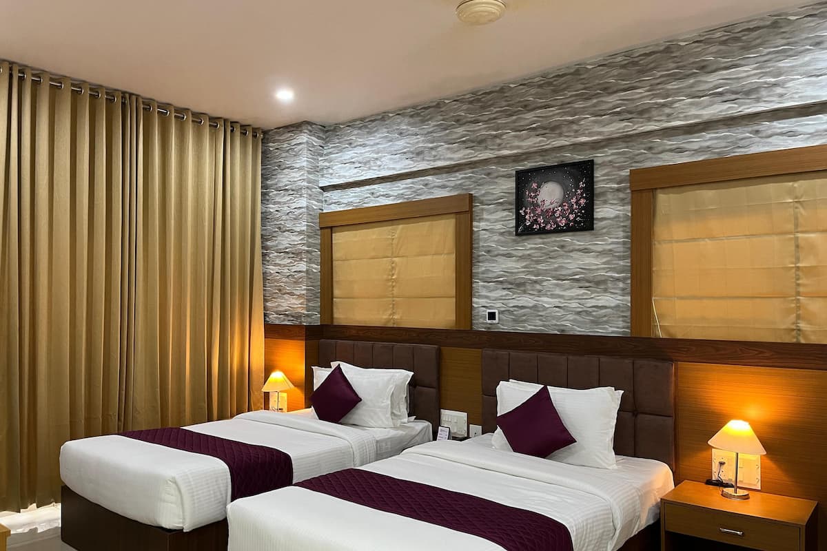 A hotel room with two beds, a large window with a view, a wall-mounted artwork, and a nightstand with a lamp.