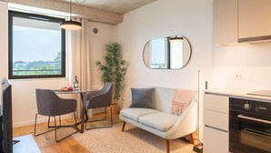 Een moderne woonkamer met een bank, stoelen, een eettafel en een keukenhoek.