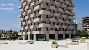 Een hoog gebouw met een modulair, herhalend gevelontwerp en balkons.
