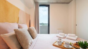 Een hotelkamer met een bed, een ontbijtplateau, handdoeken en uitzicht op de lucht.