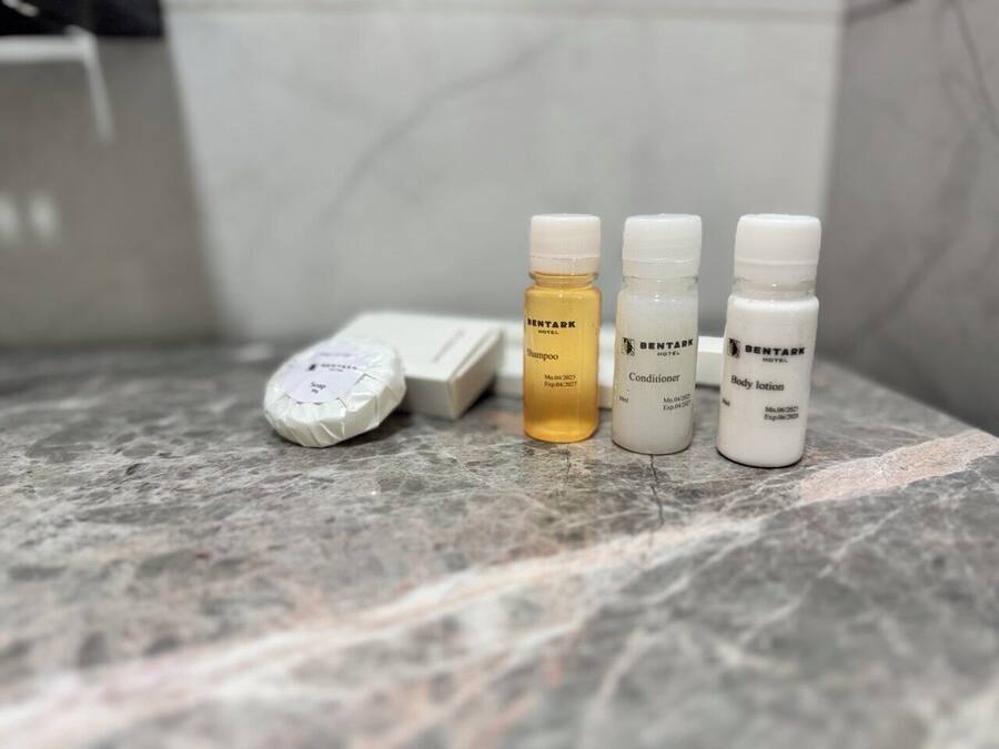 Een badkamermeubel met toiletartikelen, zoals een zeepstaaf, een shampoo, conditioner en bodylotion.