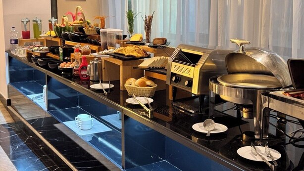 A buffet setup with various food items, condiments, and cooking equipment. - Bentark Hotel  (Addis Ababa)