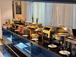 Una mesa de buffet con distintos alimentos, salsas y utensilios de cocina.
