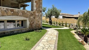 Ein modernes Haus mit Steinaußenwand, einer überdachten Terrasse und einem gepflegten Rasen mit einem Steinweg.
