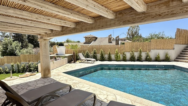 Ein Poolbereich mit Liegestühlen und einer Pergola.