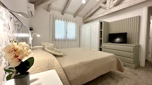Ein Schlafzimmer mit einem Bett, einem Fernseher, einem Schminktisch und einem Fenster mit Vorhängen.