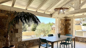 Eine Terrasse im Freien mit einer Steinwand, einer Holzbeschichtung und einem Tisch mit Stühlen.