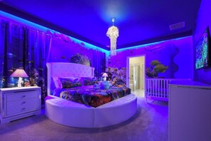 A round bed with a white headboard in a room with blue lighting and an aquarium. - Amazing 10BR Jurassic World in Windsor Island (Davenport)